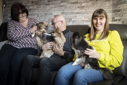 Foto van het ondersteunend pleeggezin Reinhilde en Freddy, samen met Dora en de hondjes in de huiskamer