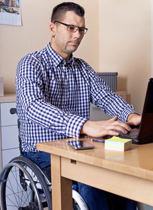 man in rolstoel aan het werken op zijn laptop